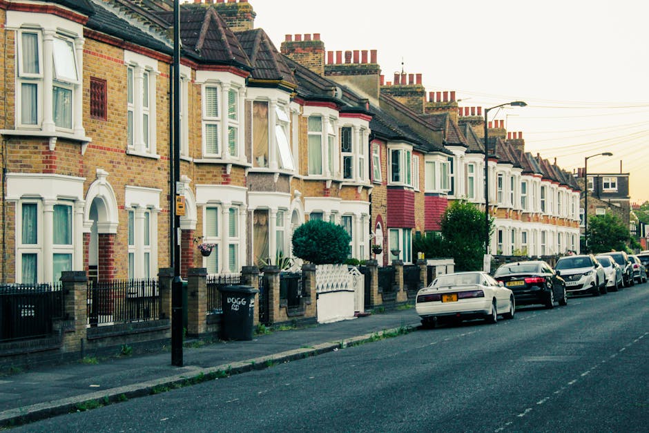 A row of traditional terraced houses on Stroud Green Road in Finsbury Park, featuring brick and painted facades with white window frames and bay windows. The front gardens are enclosed by low brick an