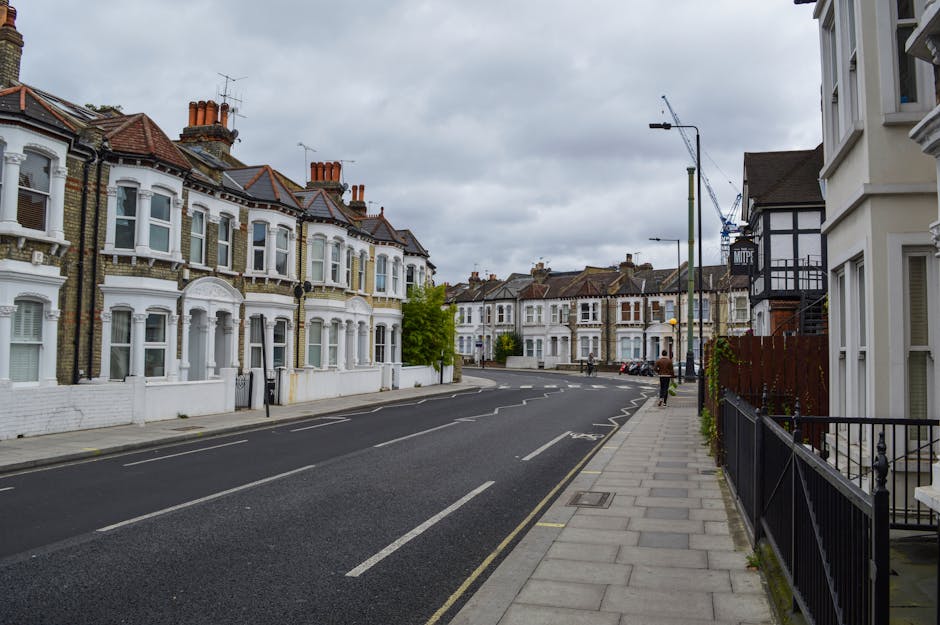 A row of traditional terraced houses on Stroud Green Road in Finsbury Park, featuring brick and painted facades with white window frames and bay windows. The front gardens are enclosed by low brick an